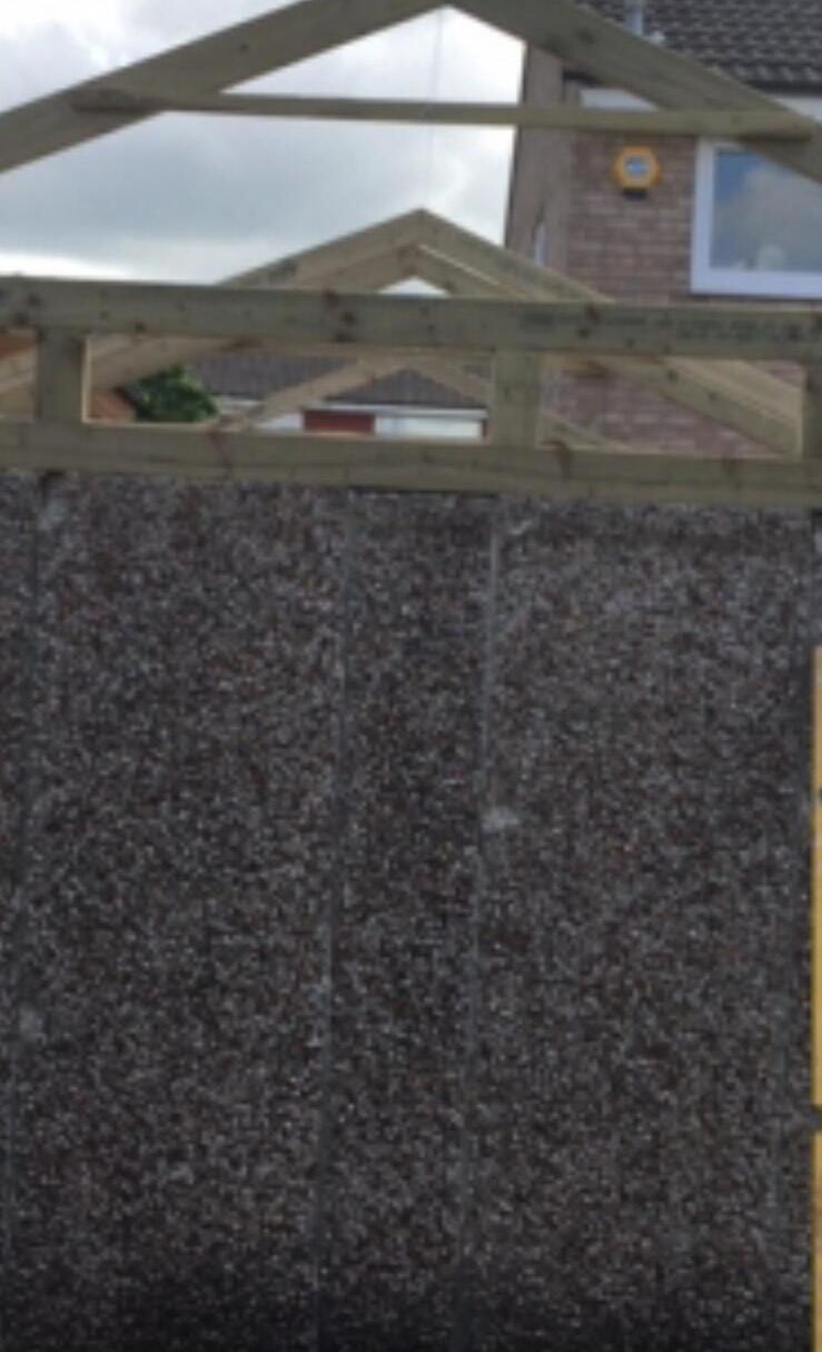 Pebbledash gable wall with new roof structure being built above