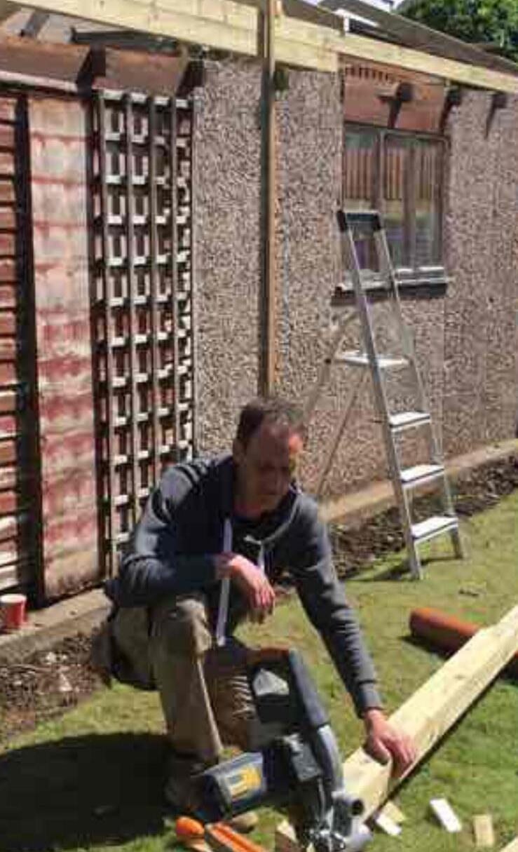 Tradesman carrying out joinery work with a mitre saw in a garden