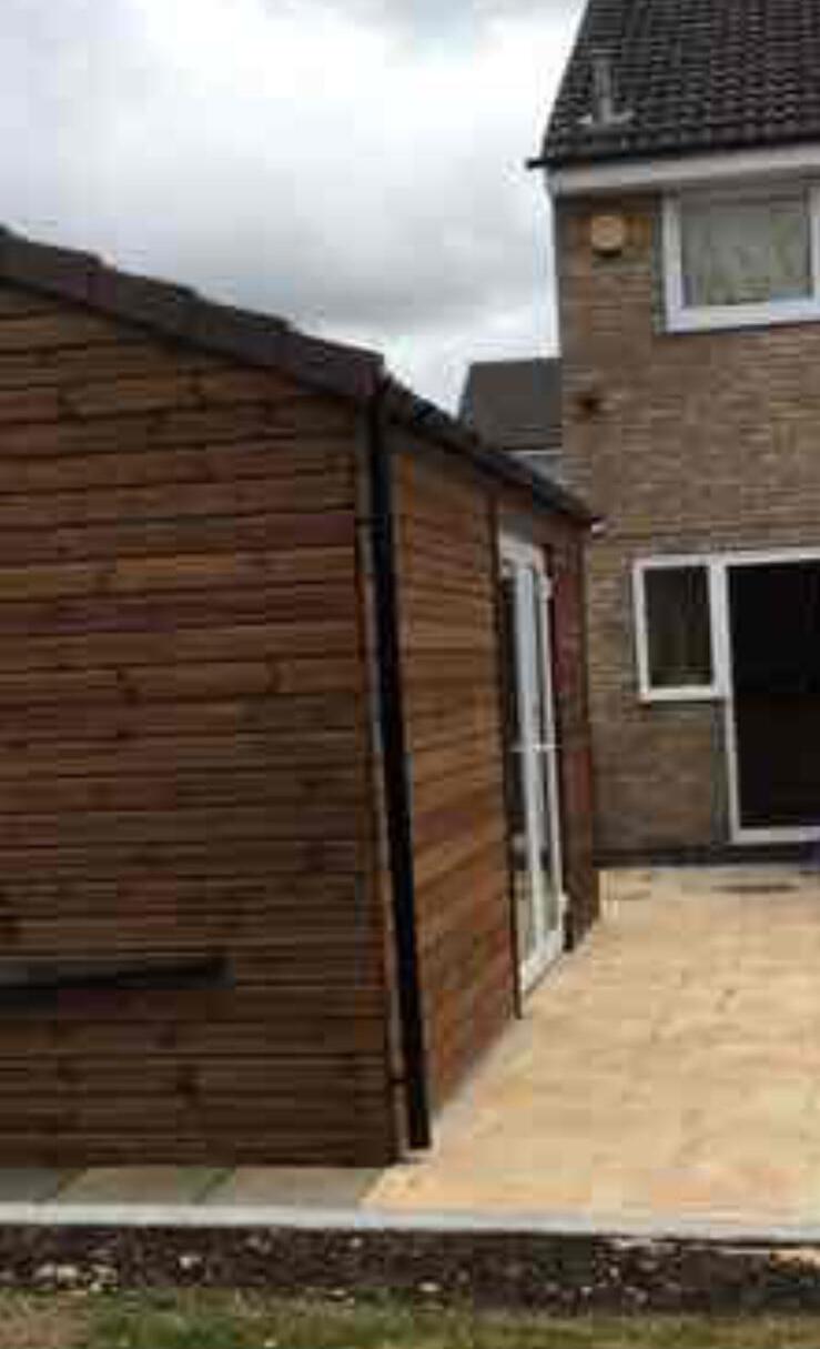 Side view of a completed timber clad garden room next to the house